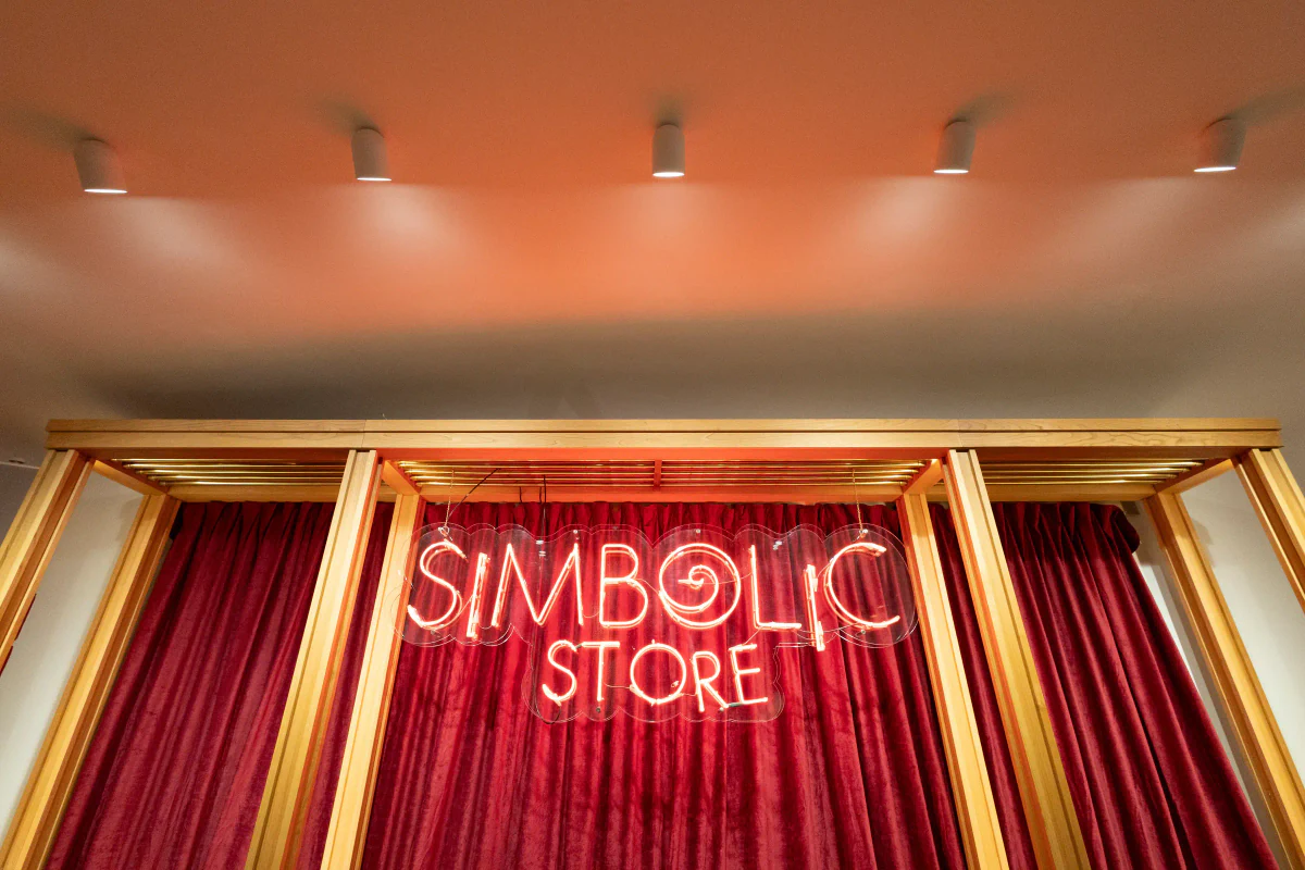 Entrada a la Simbòlic Store de Casa Batlló con cortinas rojas, rótulo luminoso y focos en el techo